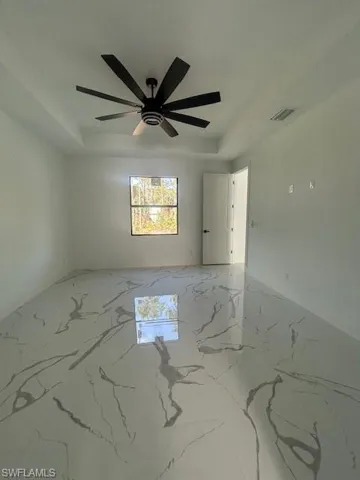 Empty room with light marble finish flooring and a raised ceiling