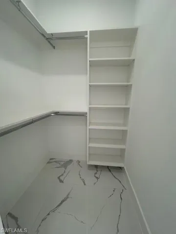Walk in closet featuring light marble finish floors