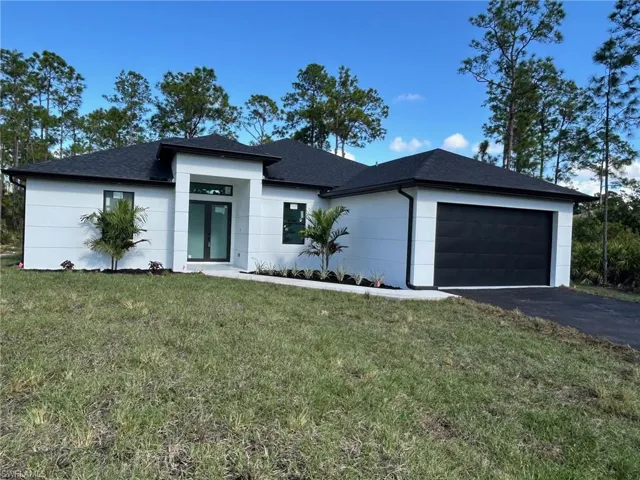 View of front of home featuring a front lawn, asphalt driveway, roof with shingles, and a garage