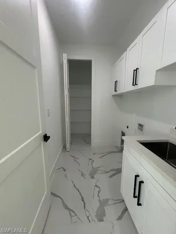Laundry room with cabinet space, washer hookup, and light marble finish flooring