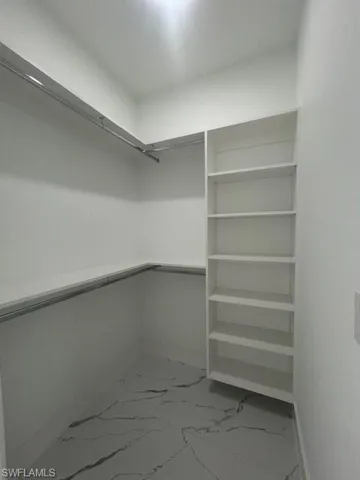 Walk in closet with light marble finish floors