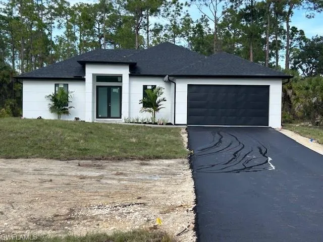View of front of property with asphalt driveway, a front lawn, an attached garage, and roof with shingles