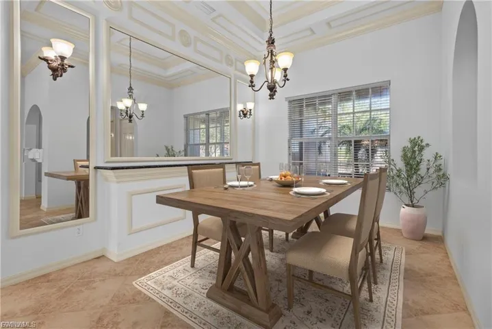 Dining area featuring arched walkways, ornamental molding, and a chandelier