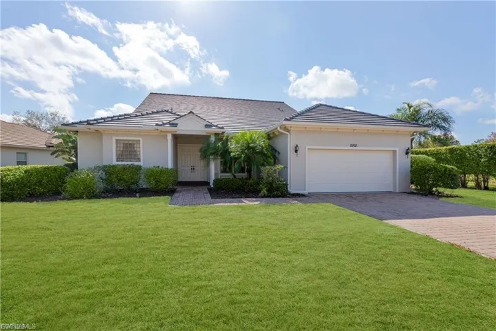 View of front facade featuring a front lawn, a garage, driveway, stucco siding, and a tiled roof