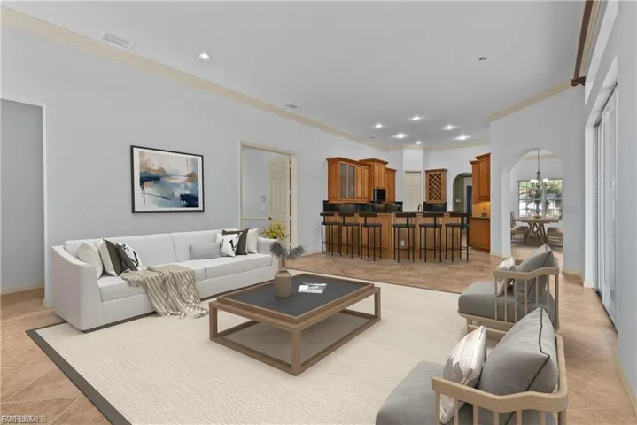 Living room featuring crown molding, arched walkways, light tile patterned flooring, and a chandelier