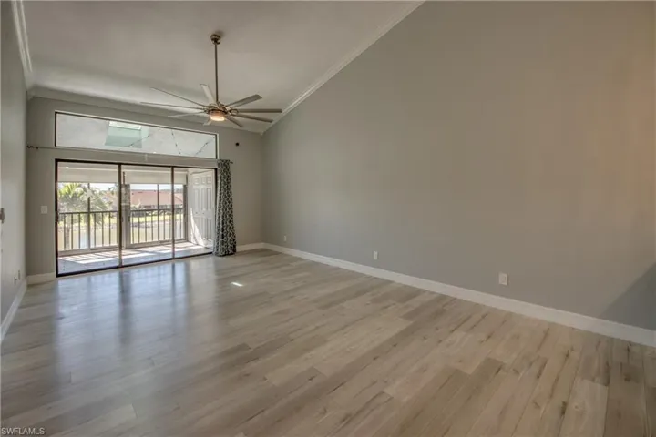 Unfurnished room with crown molding, ceiling fan, light wood finished floors, and high vaulted ceiling
