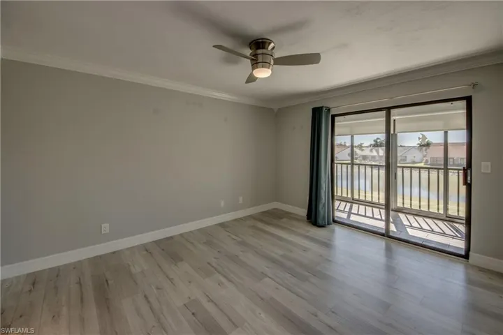 Empty room featuring ornamental molding, ceiling fan, light wood finished floors, and a residential view