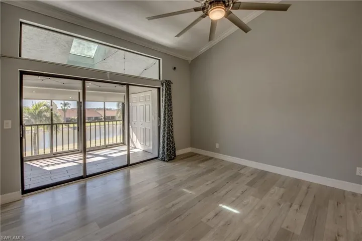 Spare room with crown molding, a skylight, vaulted ceiling, light wood-style floors, and ceiling fan