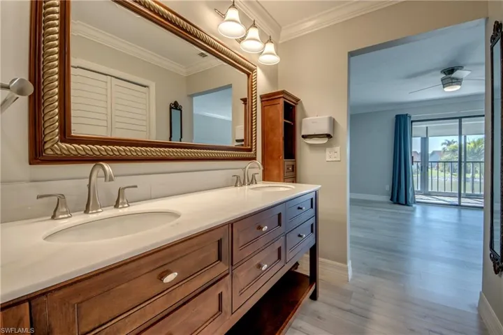 Full bathroom with crown molding, double vanity, ceiling fan, and light wood-style flooring