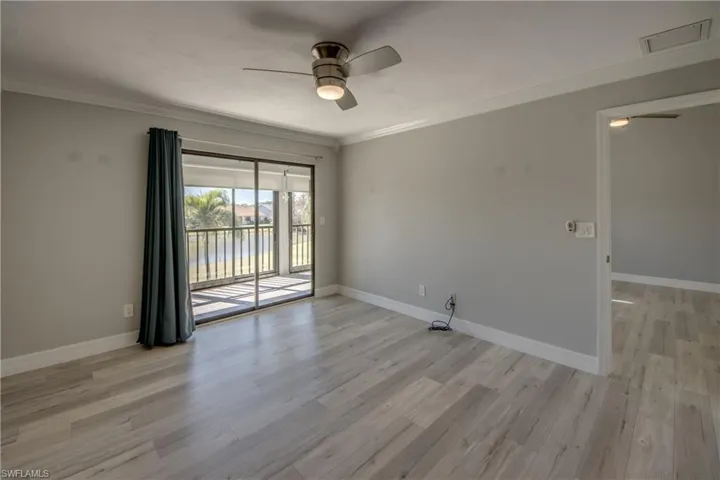 Empty room featuring ceiling fan, light wood finished floors, and crown molding