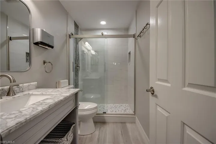 Full bath with vanity, a shower stall, and light wood-style flooring