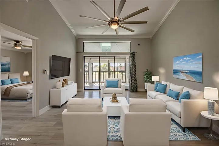 Living room featuring ceiling fan, light wood-type flooring, crown molding, and a high ceiling