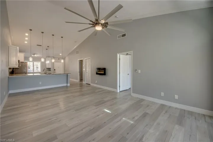 Unfurnished living room with high vaulted ceiling, recessed lighting, light wood-style floors, crown molding, and a ceiling fan