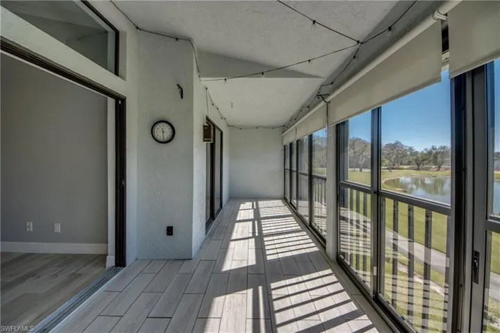 Unfurnished sunroom featuring a water view, wood finish floors, and a textured wall