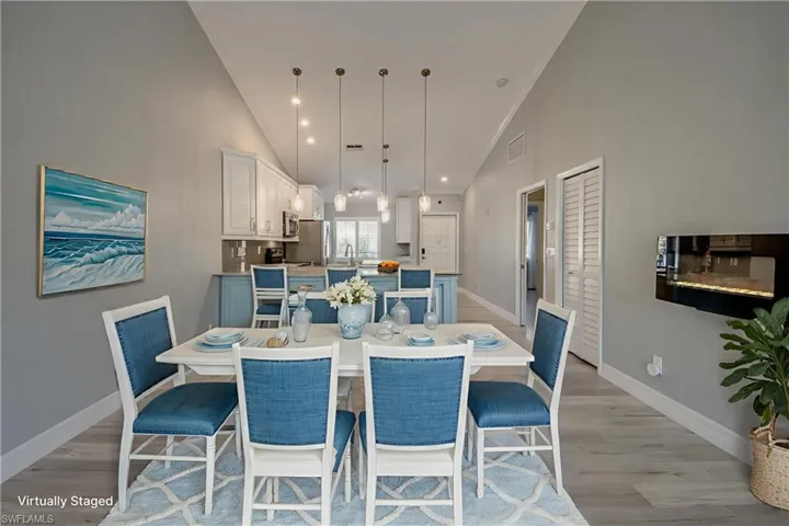 Dining room featuring light wood finished floors, high vaulted ceiling, crown molding, and recessed lighting