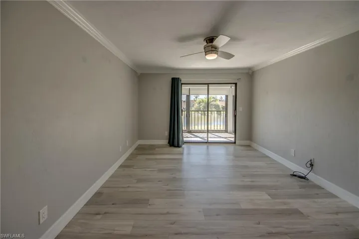 Unfurnished room with light wood finished floors, crown molding, and a ceiling fan