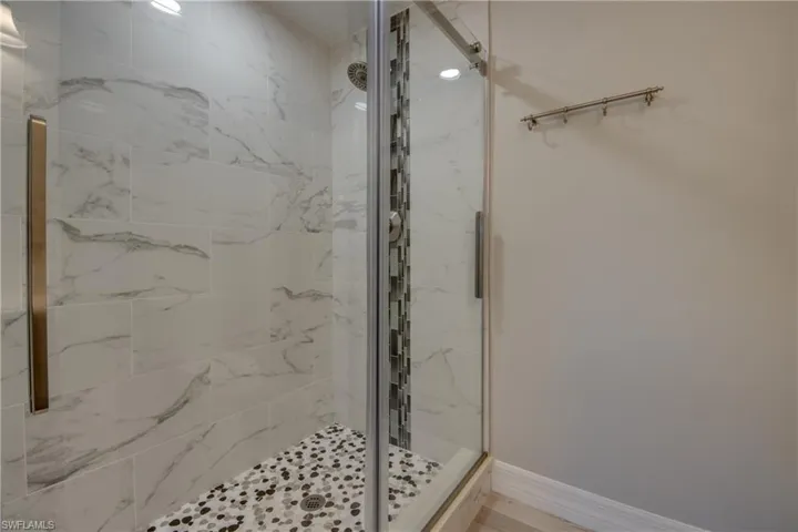 Full bath with a marble finish shower and baseboards