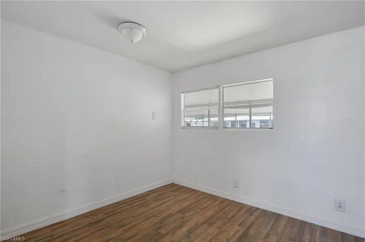 Unfurnished room featuring baseboards and dark wood-type flooring