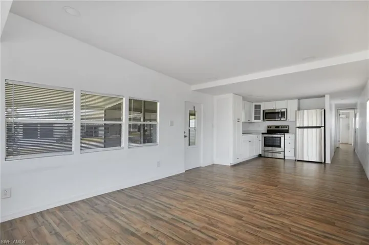 Unfurnished living room with baseboards and dark wood-type flooring