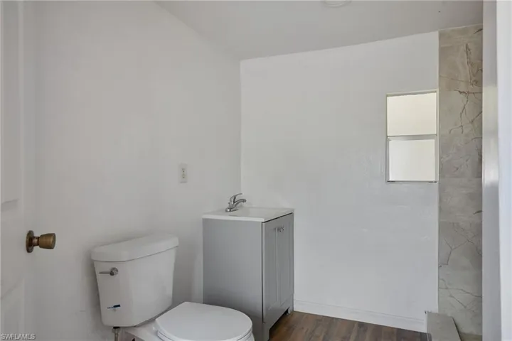 Full bath with vanity, wood finished floors, and toilet