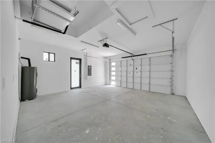 Spacious garage featuring a concrete floor, white painted walls, and a modern garage door with frosted glass panels
