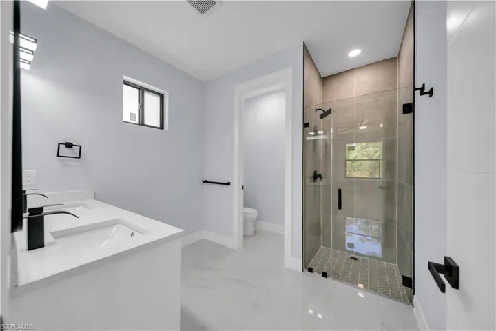 Contemporary bathroom featuring a spacious glass-enclosed shower with tiled walls and a herringbone-patterned shower pan