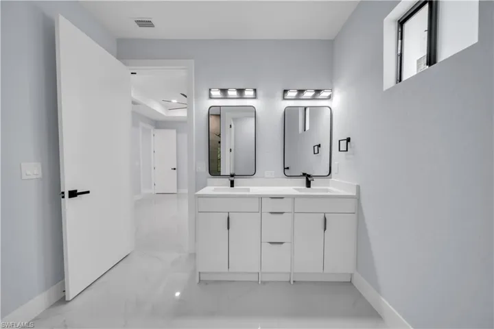 Dual vanity with white cabinetry, integrated sinks, black framed mirrors, and contemporary wall sconces
