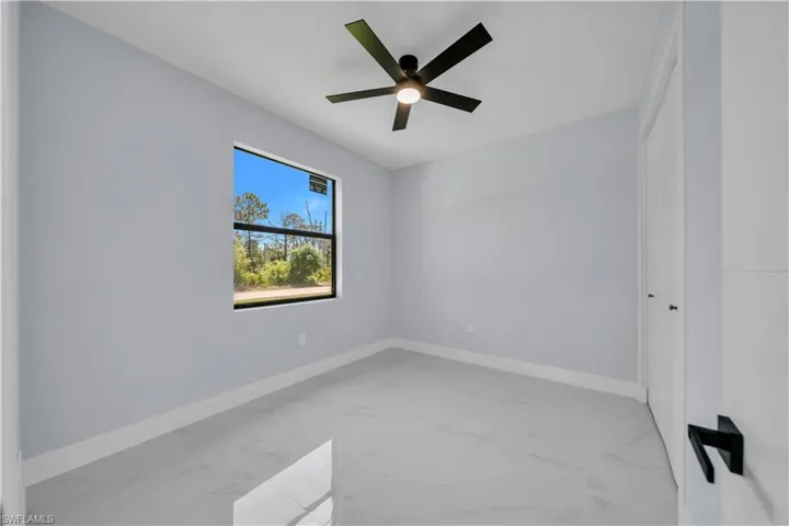 Bright room featuring a single window, a contemporary ceiling fan, and light-toned flooring