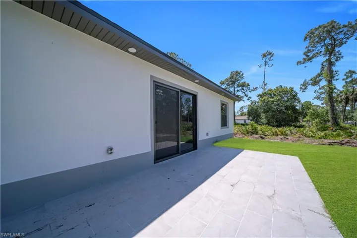 Expansive patio featuring light-toned rectangular paving stones and direct access to a grassy area