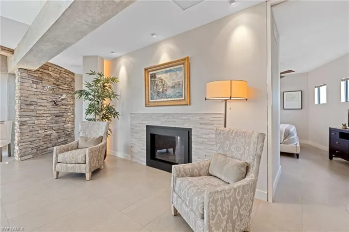 Living area featuring a glass covered fireplace and light tile patterned floors