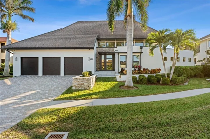 View of front of home featuring a garage, decorative driveway, a front lawn, and stucco siding