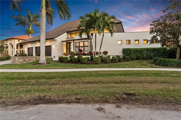 View of front of property featuring an attached garage, a front lawn, stucco siding, and driveway