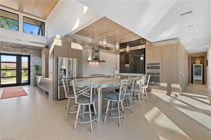 Dining space with light tile patterned flooring, wood ceiling, wine cooler, a high ceiling, and recessed lighting