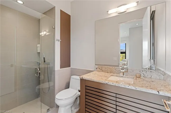 Full bathroom with vanity, a stall shower, tile walls, recessed lighting, and wainscoting