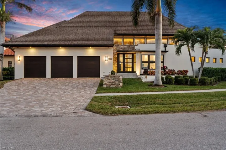 View of front facade with an attached garage, driveway, a yard, stucco siding, and french doors
