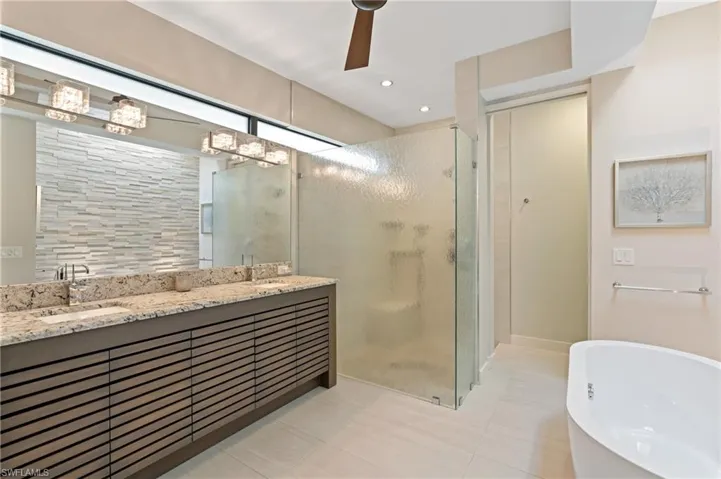 Bathroom with a shower stall, double vanity, a soaking tub, a ceiling fan, and tile patterned flooring