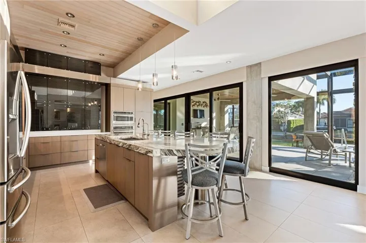 Kitchen with modern cabinets, a spacious island, appliances with stainless steel finishes, a breakfast bar area, and light tile patterned floors