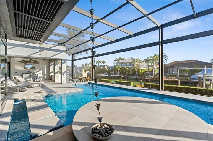 Swimming pool featuring a patio area, glass enclosure, and a residential view