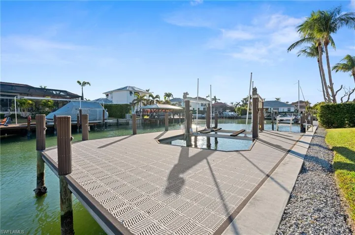 Dock featuring boat lift, a water view, and a residential view