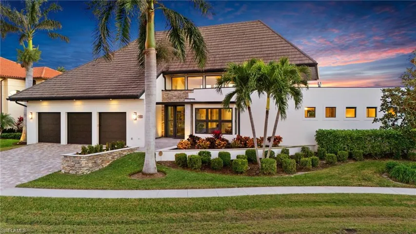 View of front of property with a garage, decorative driveway, a yard, stucco siding, and a balcony