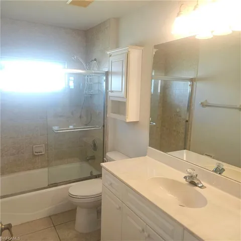 Full bathroom featuring vanity, light tile patterned floors, and bath / shower combo with glass door