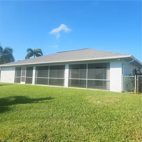 Back of property with stucco siding, a yard, a sunroom, and roof with shingles