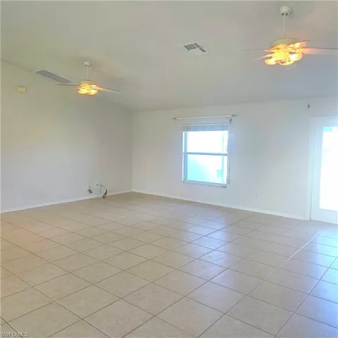 Spare room with ceiling fan, light tile patterned floors, and lofted ceiling