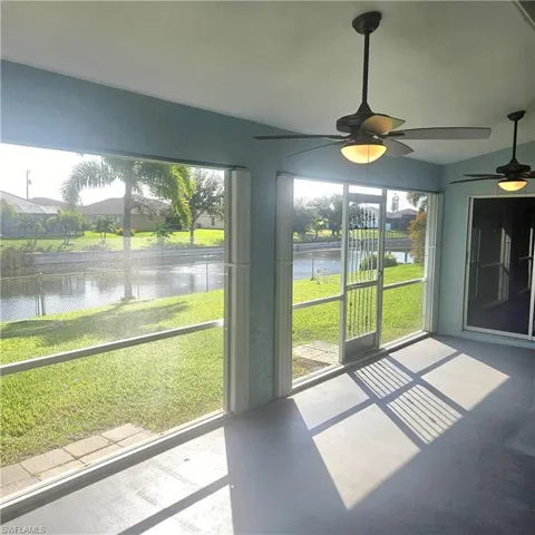 Unfurnished sunroom featuring ceiling fan, a water view, and vaulted ceiling