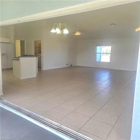 Unfurnished room featuring ceiling fan, hanging lights, light tile patterned floors, lofted ceiling, and washer / clothes dryer