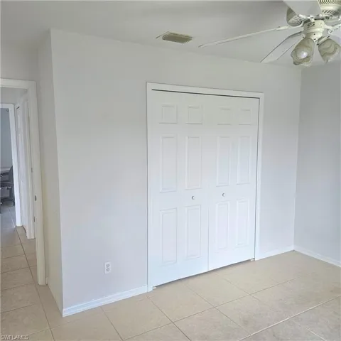 Unfurnished bedroom with light tile patterned flooring, a closet, and a ceiling fan