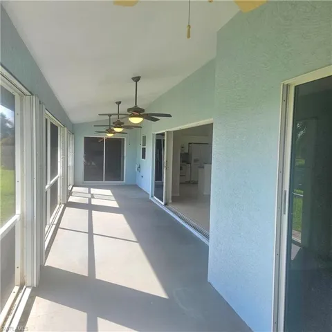 Unfurnished sunroom with a ceiling fan and vaulted ceiling