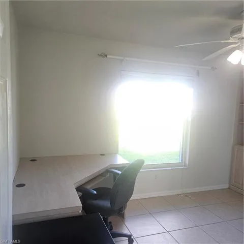 Office with a ceiling fan and light tile patterned floors
