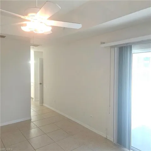Empty room with ceiling fan and light tile patterned floors