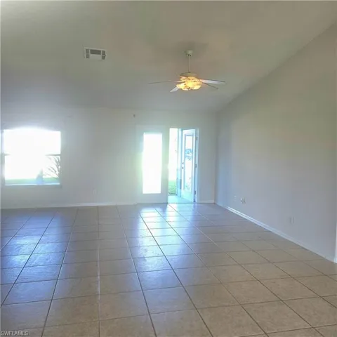 Empty room featuring a ceiling fan, light tile patterned floors, and vaulted ceiling